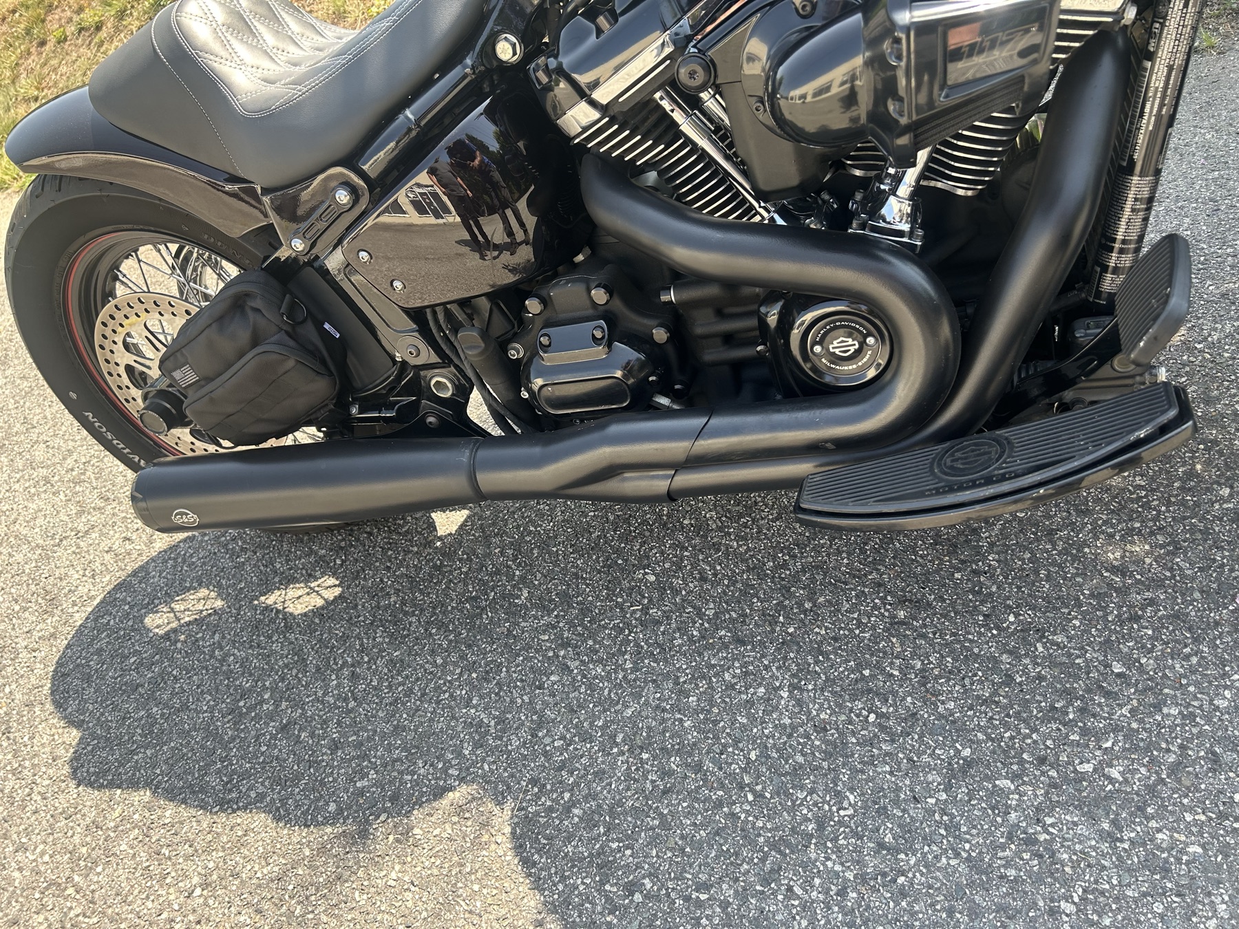 Detail of a matte black exhaust and floorboard on a custom Harley-Davidson