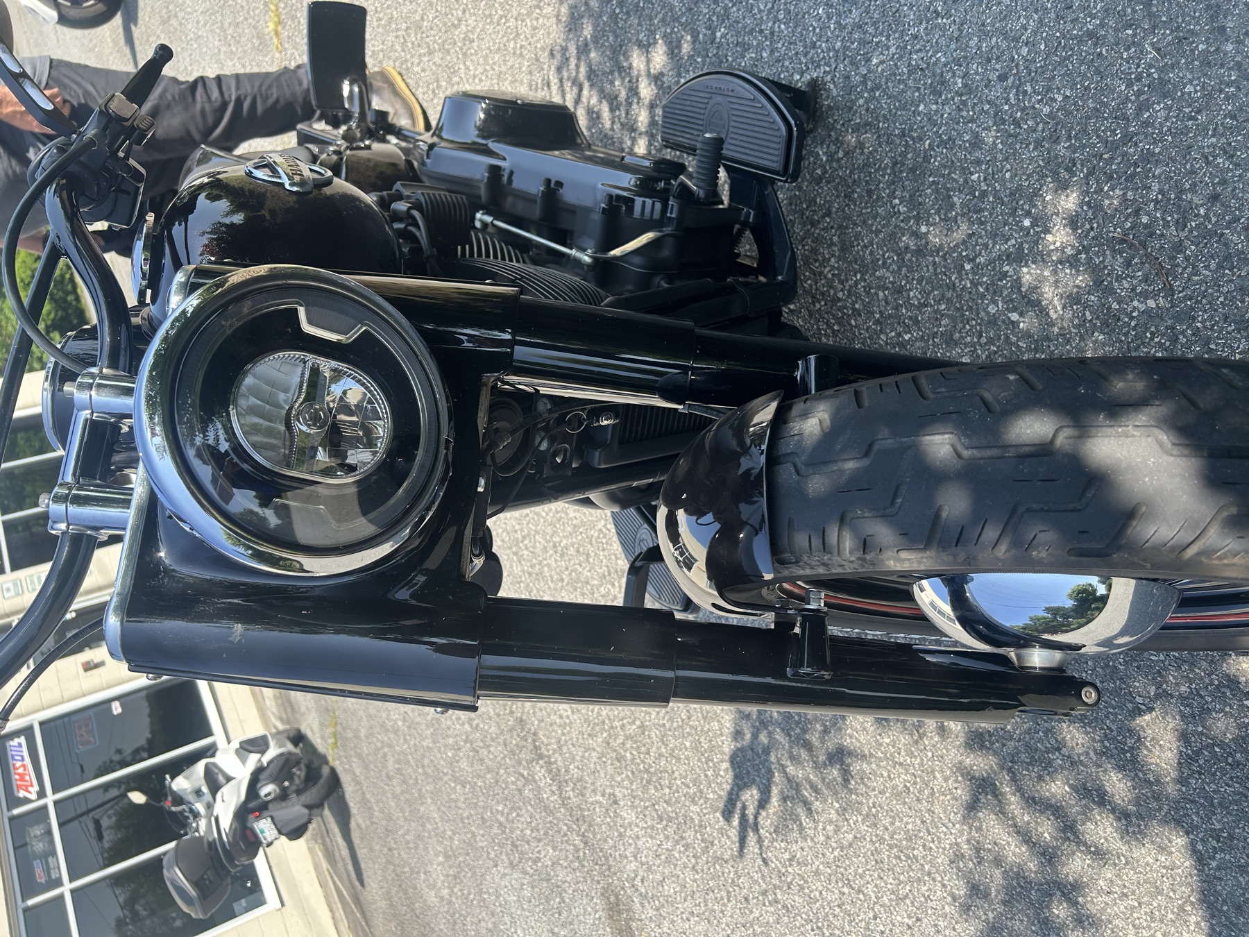 Front view of a blacked-out Harley-Davidson with LED headlight in front of the shop