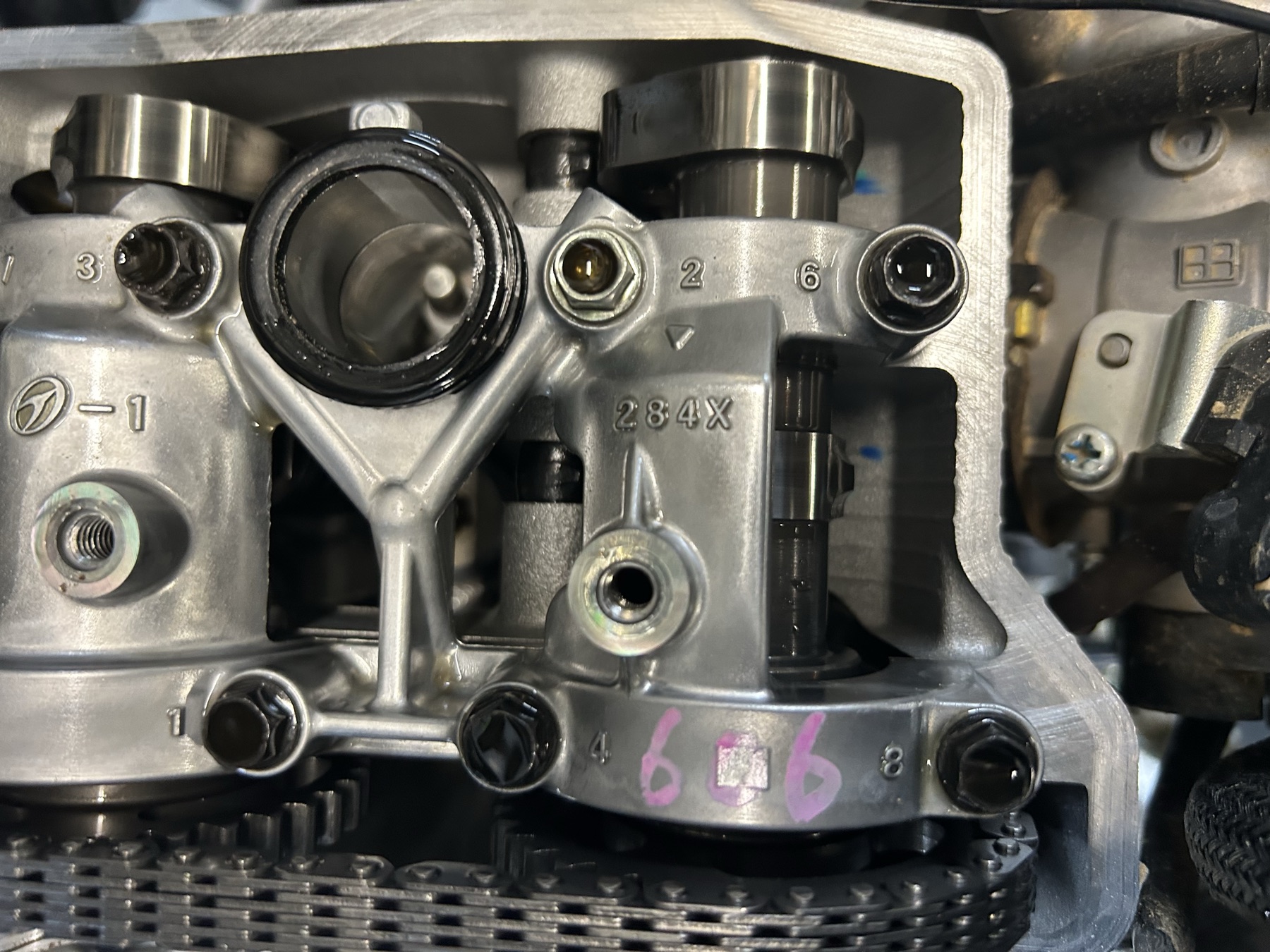 Motorcycle engine top end opened up on the bench, showing camshaft and valve train during a rebuild